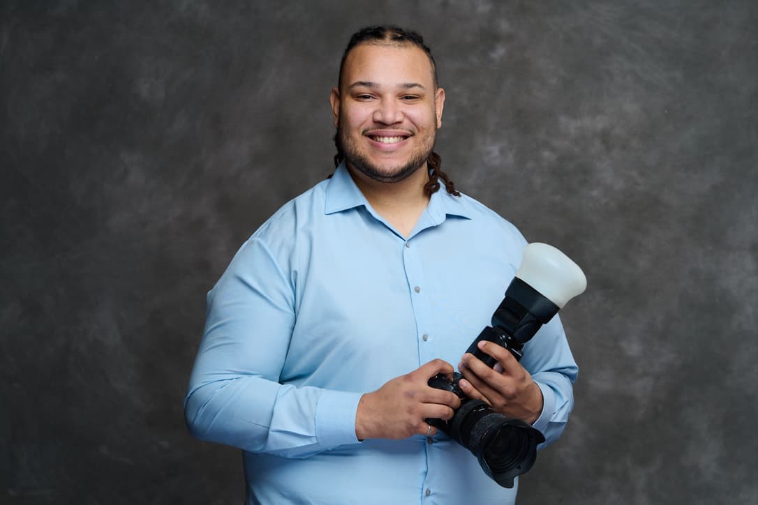Carter McKinney, founder of McKinney Media, smiling in a blue shirt and holding a camera