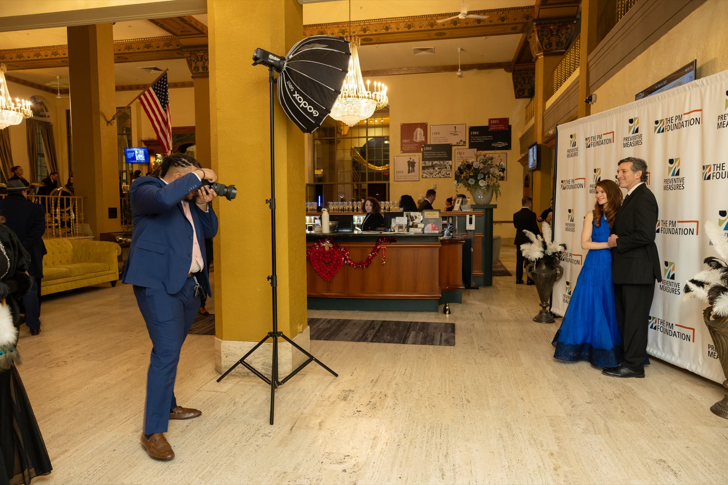 Carter McKinney photographing a couple in front of a sponsor backdrop at a formal event