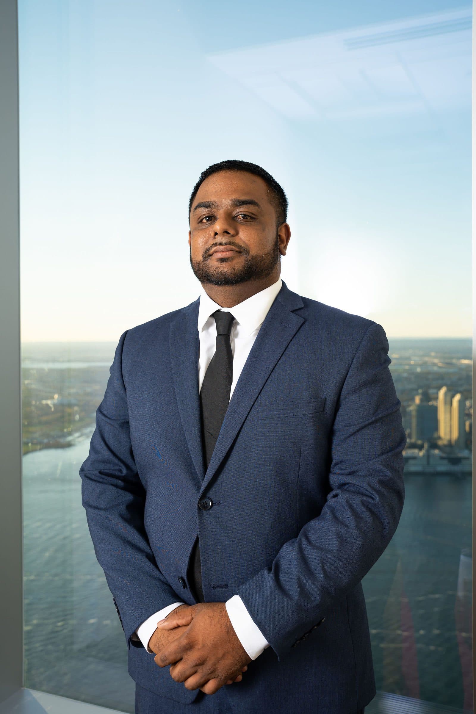 Executive portrait in a navy suit in front of a window with a river view