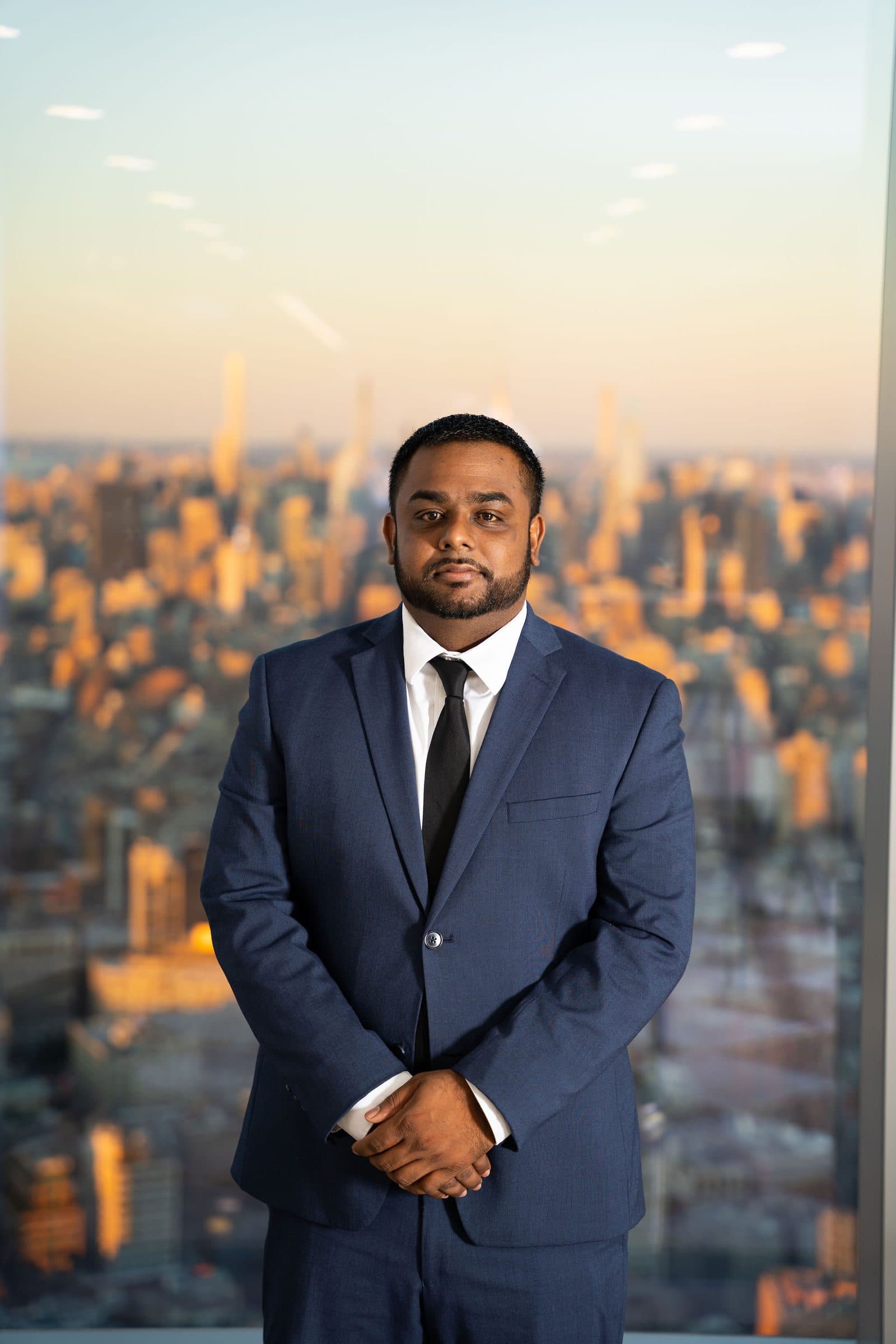 Executive portrait in a navy suit against a city skyline at sunset