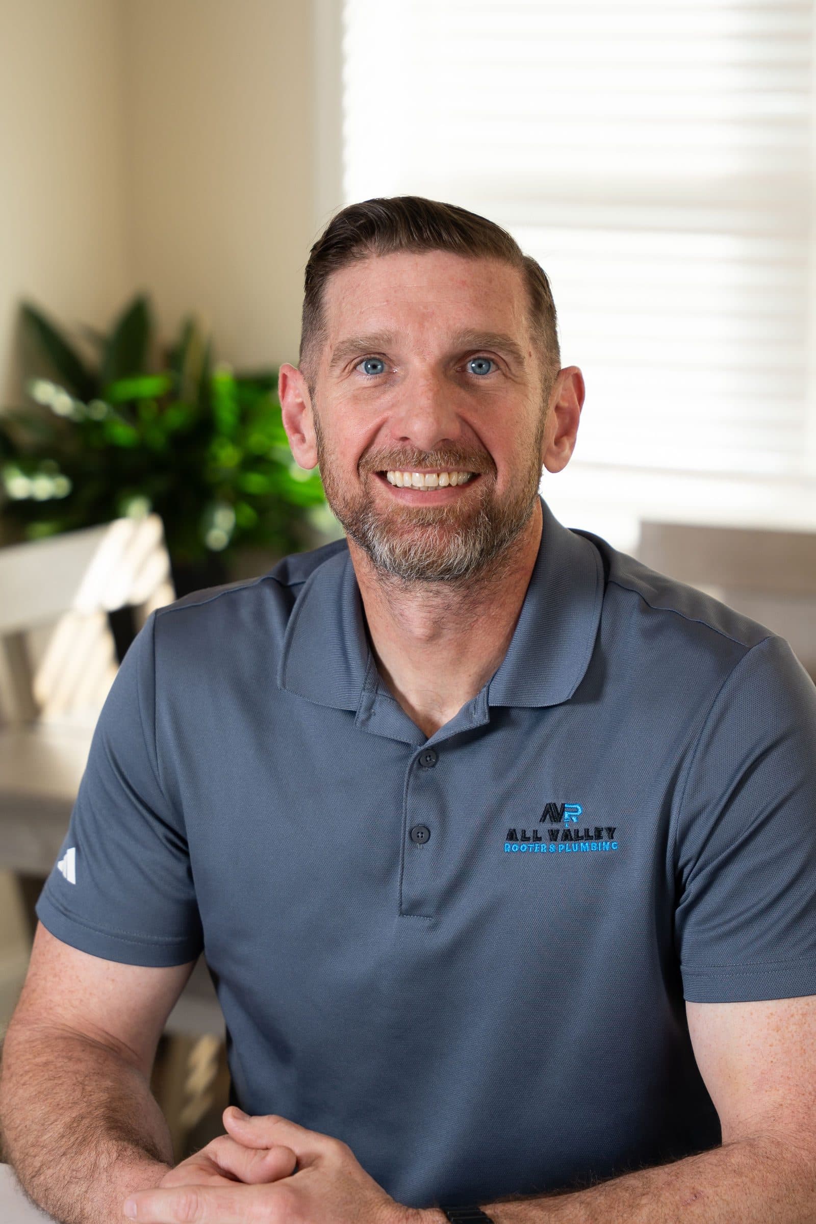 Headshot in an All Valley Rooter polo, seated at a table