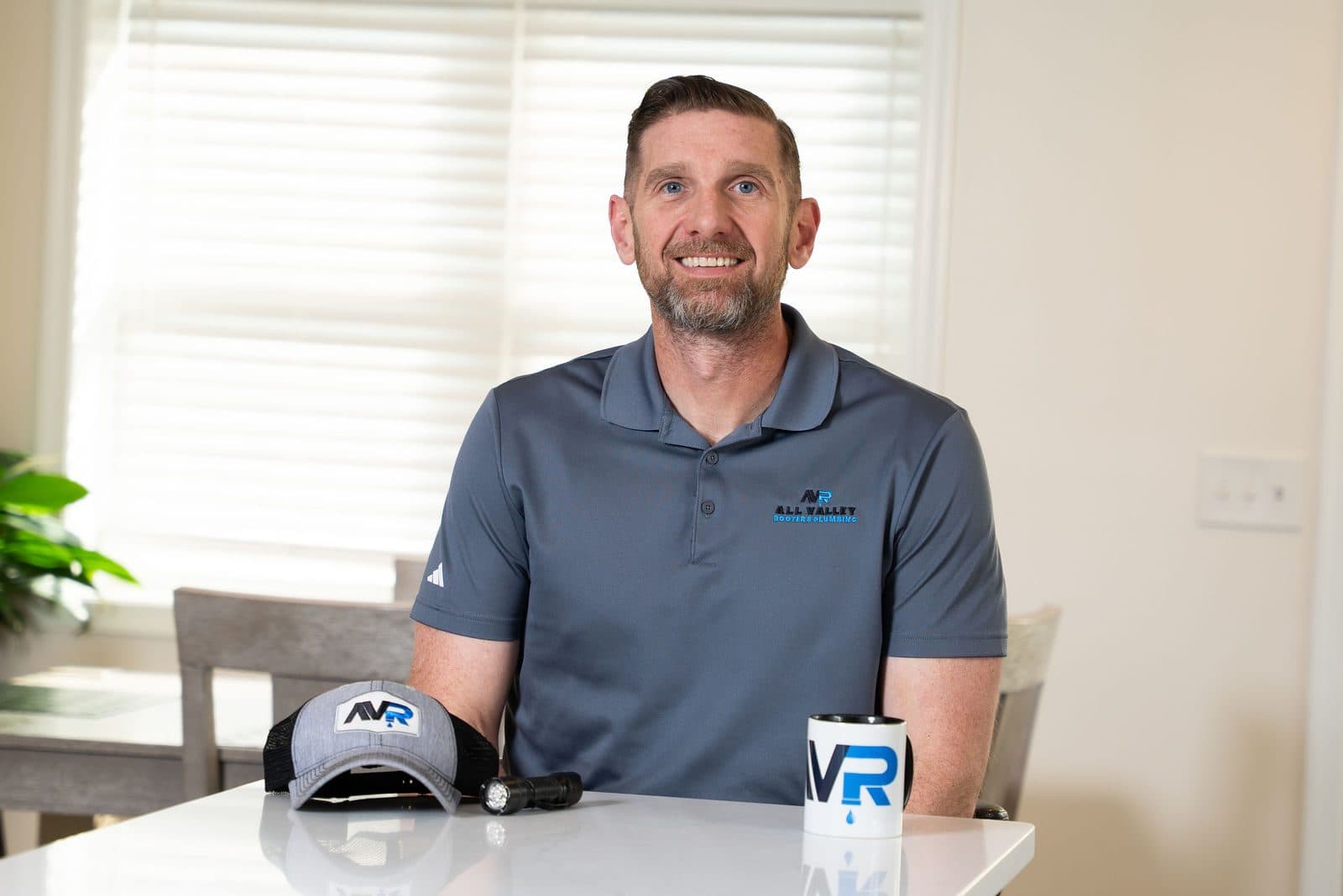 Portrait at a table with an All Valley Rooter hat and branded cup
