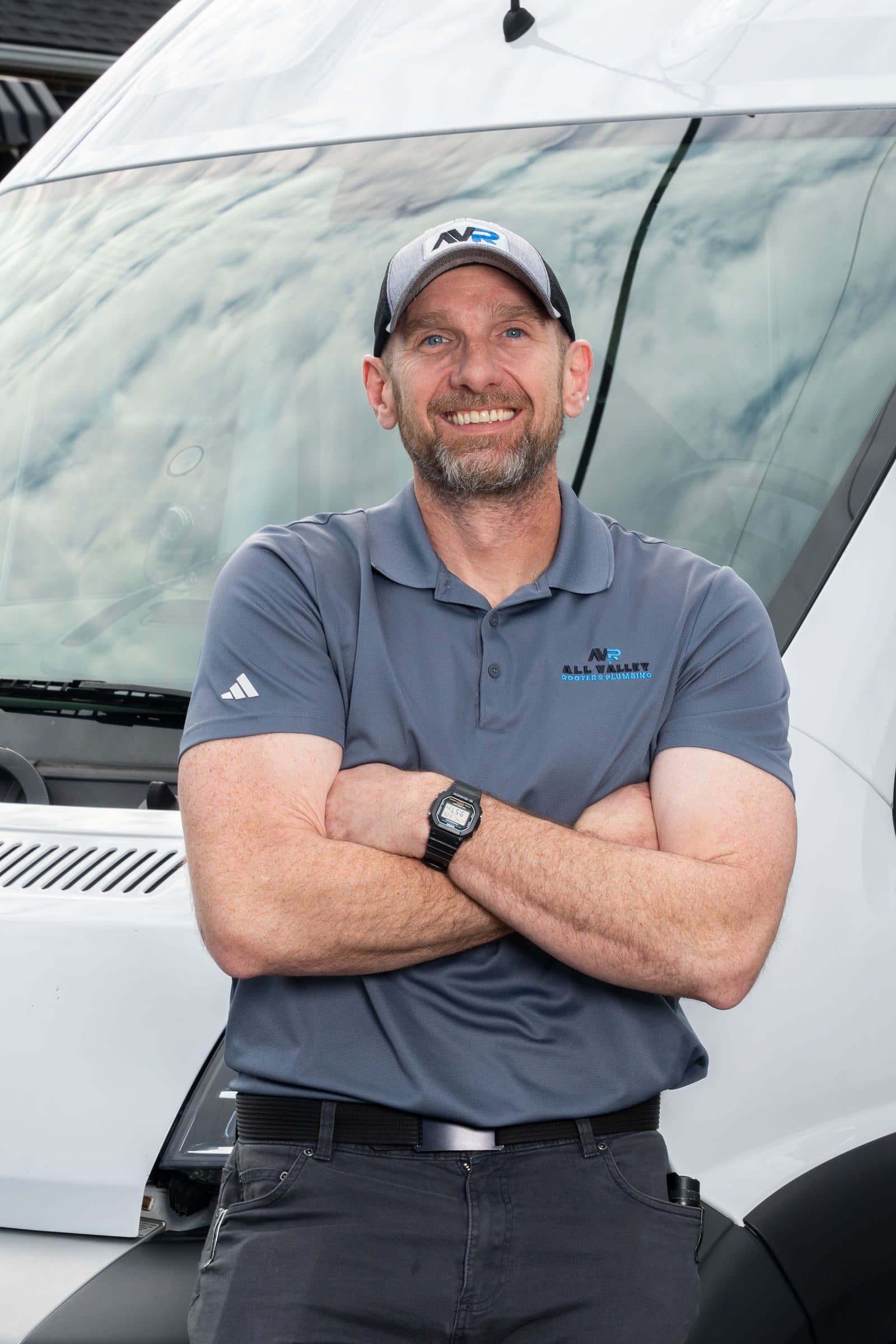 Arms-crossed portrait in front of the All Valley Rooter van